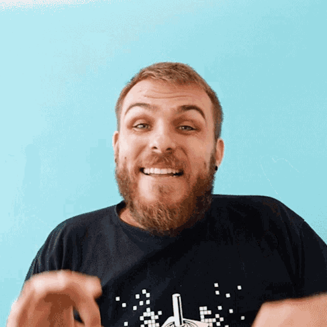 a man with a beard is wearing a black shirt with a pixelated hand pointing up