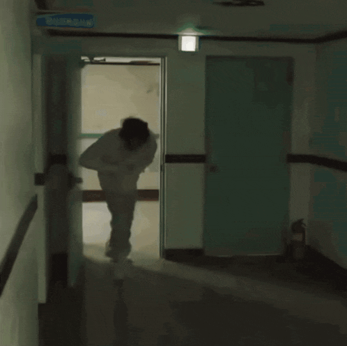 a man in a white shirt and tie is walking down a hallway