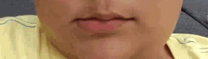 a close up of a person 's face with a yellow shirt on .