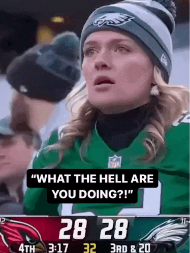 a woman wearing a green eagles jersey is watching a football game