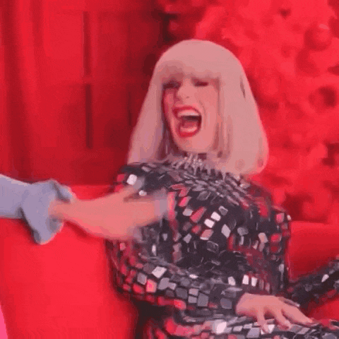 a woman in a sequined dress is sitting on a red couch being touched by a man .