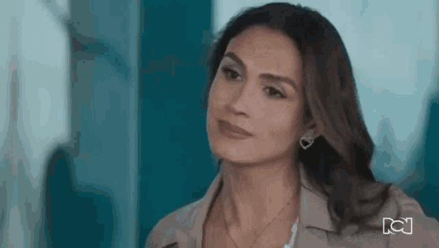 a woman wearing earrings and a necklace is standing in a room .
