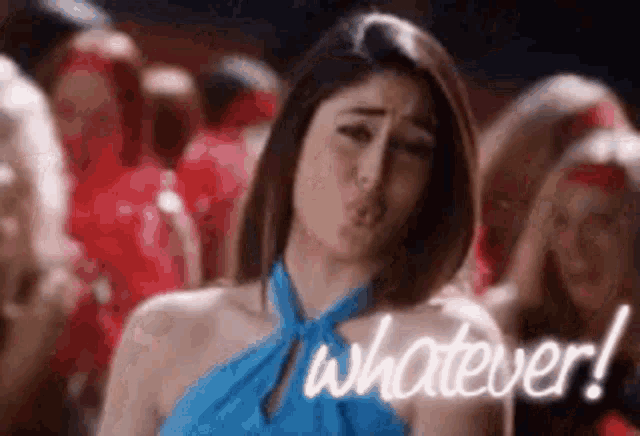 a woman in a blue dress is blowing a kiss while standing in front of a crowd .