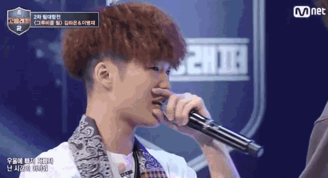 a young man is singing into a microphone while wearing a bandana .