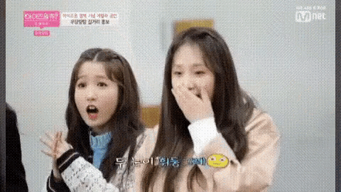 a couple of girls are standing next to each other with their mouths open .