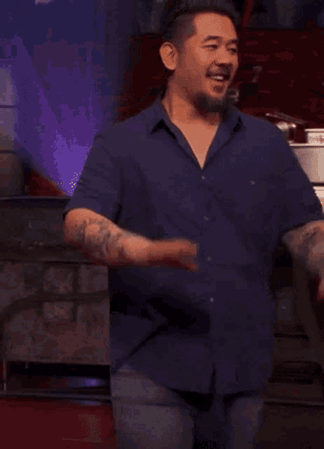 a man with a tattoo on his arm is wearing a blue shirt