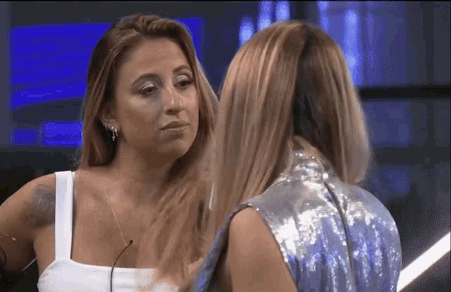 two women are standing next to each other and one is wearing a silver sequined top