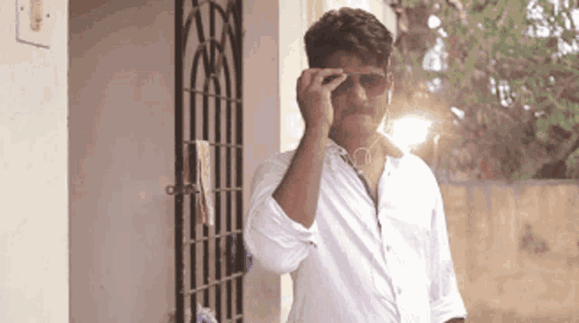 a man wearing sunglasses and ear buds is standing in front of a building