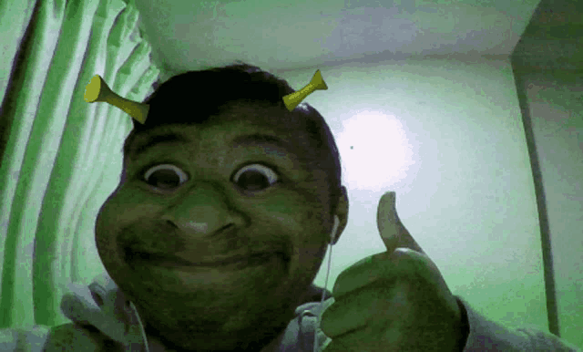 a man wearing shrek ears giving a thumbs up