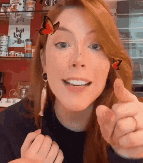 a woman with a butterfly on her face is giving a thumbs up sign