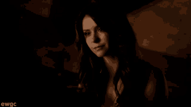 a woman 's face is shown in a dark room with ewgc written on the bottom