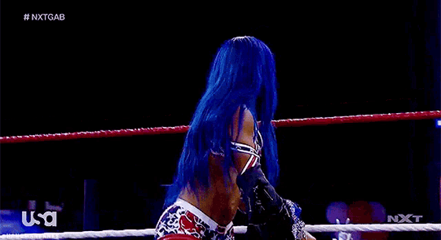a woman with blue hair is standing in a ring .