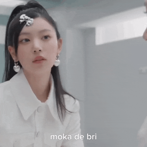 a woman wearing a white shirt and earrings is looking at another woman 's face .