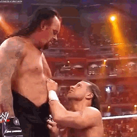 two men are wrestling in a ring and one of them is holding the other 's waist .