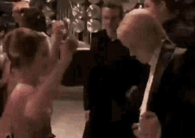 a group of people are dancing at a party in a room .