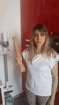 a woman is holding a wooden rolling pin in her hand