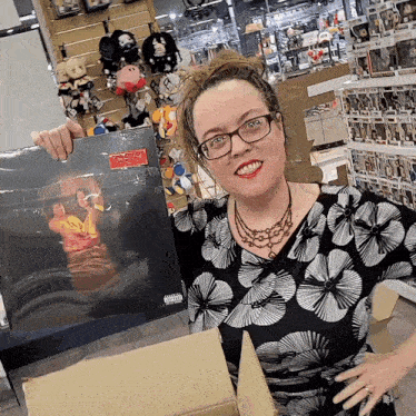 a woman in a black and white floral shirt is holding a record that says explicit