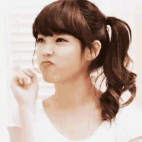 a woman with a ponytail and bangs is making a face .