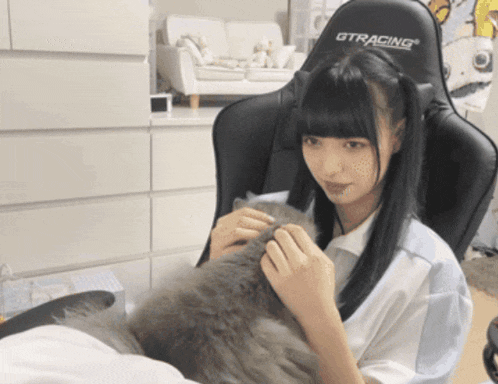 a girl petting a cat while wearing a black gtracing chair