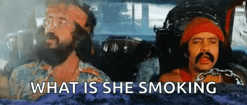 a man with a beard and mustache is smoking a cigarette while another man looks on .