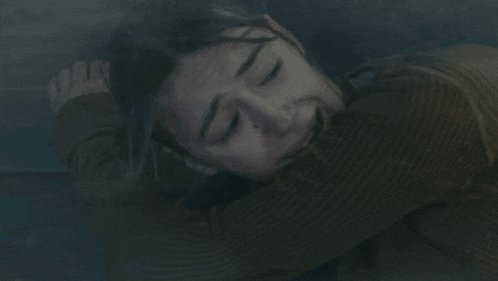 a woman is laying down with her eyes closed in a dark room .