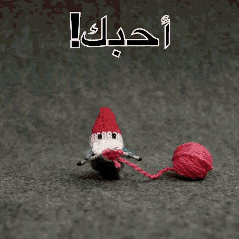 a knitted gnome is knitting with a ball of yarn