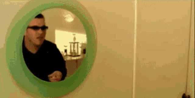 a man wearing sunglasses is looking at himself in a mirror
