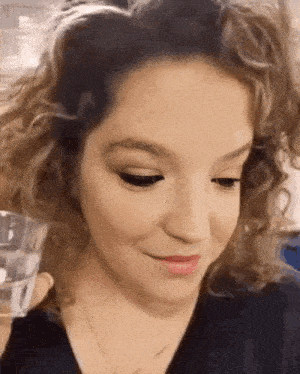 a close up of a woman 's face with a glass in her hand .