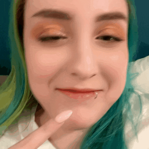 a close up of a woman 's face with blue hair