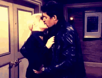 a man and a woman are kissing in a doorway