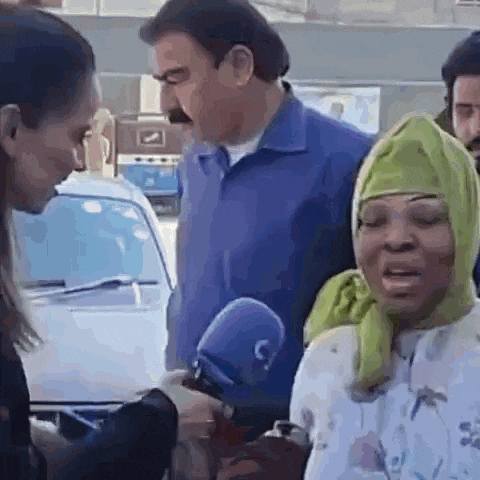 a woman wearing a green head scarf is talking to a man in a blue shirt .