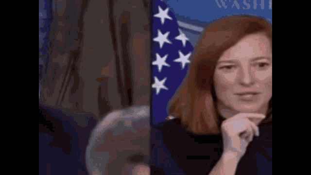 a woman with red hair is standing in front of a flag .