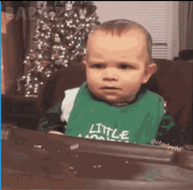 a baby is wearing a green bib that says little one on it