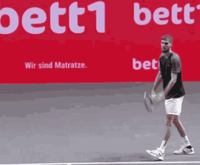 a man is holding a tennis racquet on a tennis court in front of a bett1 banner