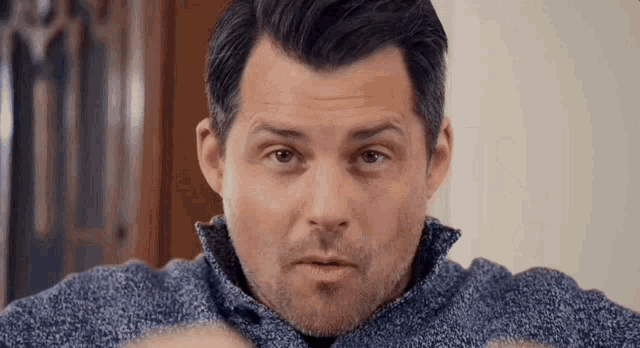 a man in a blue sweater looks at the camera