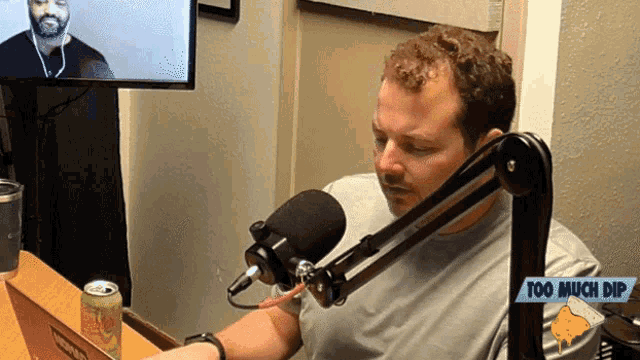 a man sitting in front of a microphone with a sign that says too much dip on it