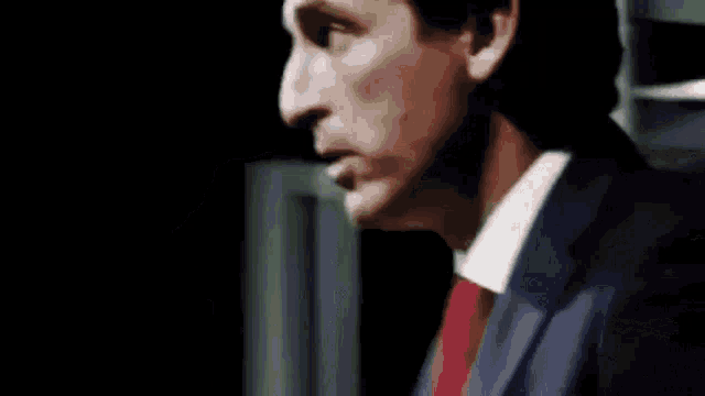 a close up of a man 's face in a suit and white shirt in a dark room .