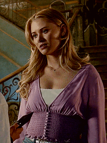 a woman in a purple sweater is standing in front of a staircase