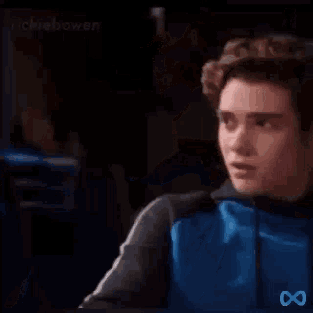a young man in a blue and black jacket is reading