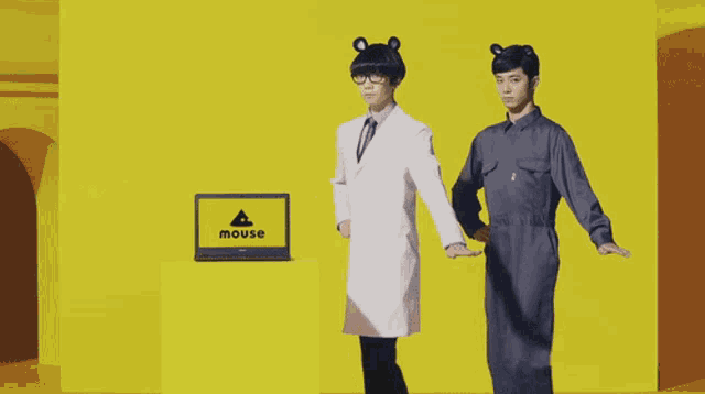 two men are standing in front of a yellow box that says mouse
