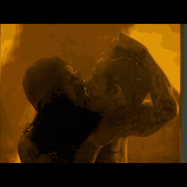a man and woman kissing in front of a yellow background
