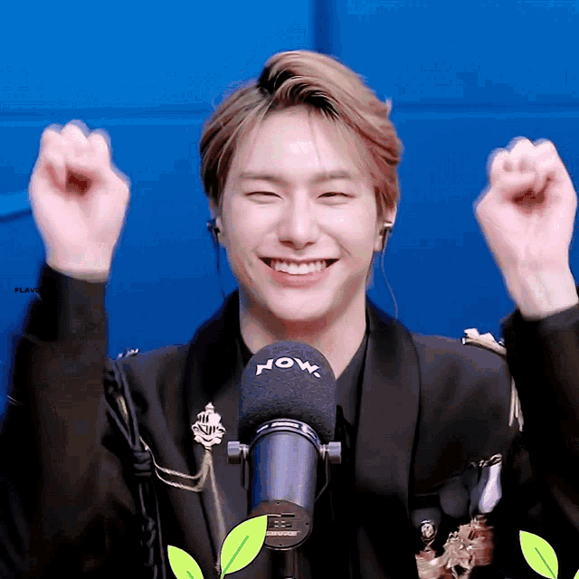 a man in a black jacket is smiling in front of a now microphone