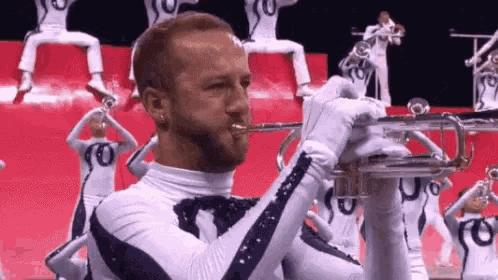 a man with a beard is playing a trumpet in front of a band .