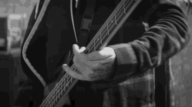 a black and white photo of a man playing a guitar