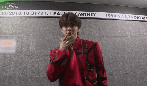 a young man in a red jacket is standing in front of a sign that says paul mccartney
