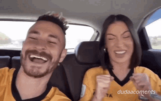 a man and woman are sitting in the back seat of a car laughing .