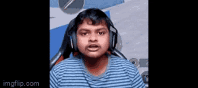 a boy wearing headphones and a striped shirt is sitting in a chair .