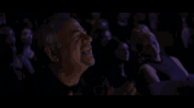 a man in a black shirt is laughing in a dark room