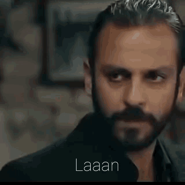 a man with a beard and mustache is looking at another man with the word laaan below him