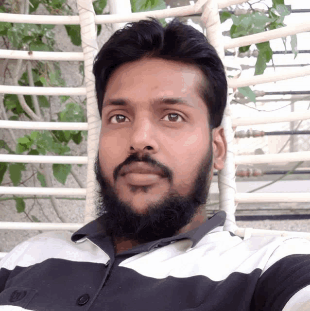 a man with a beard wears a black and white shirt